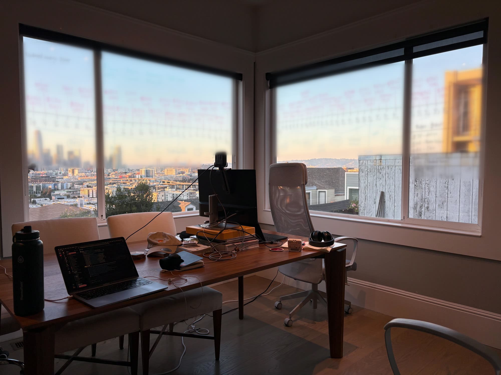 A desk in a corner room at sunset, with numbers written on the windows and the city behind